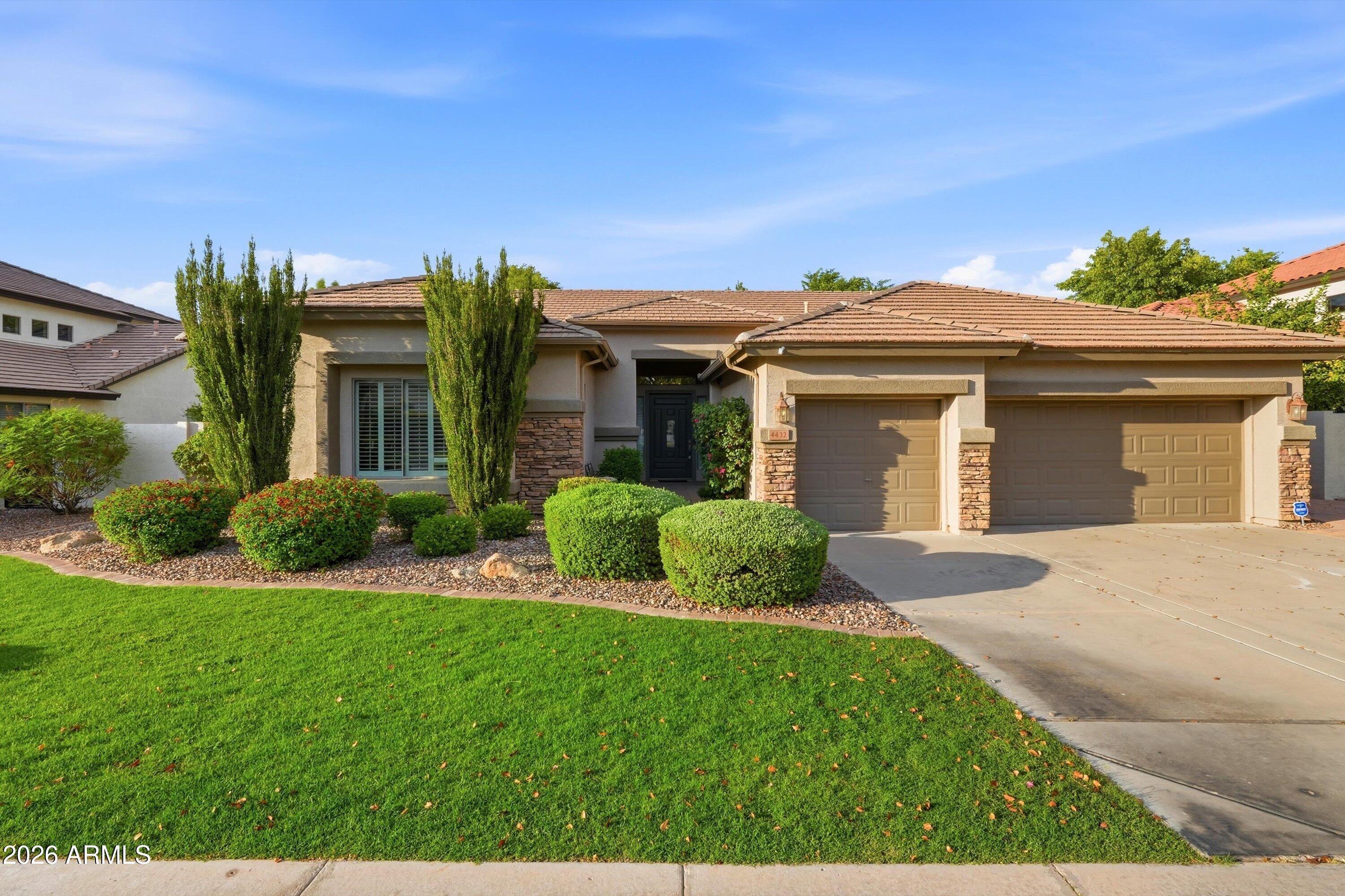 Single-story stucco home with a tile roof, two-car garage, and landscaped front lawn.