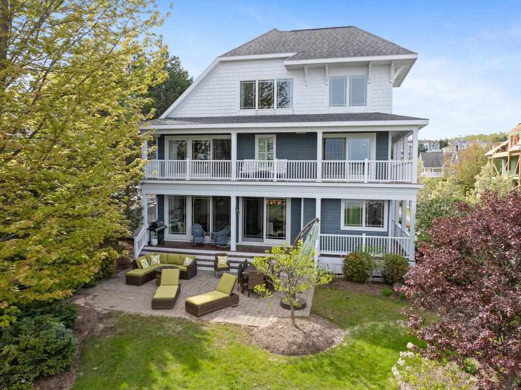 Two-story blue-gray house with white porches and a furnished stone patio.