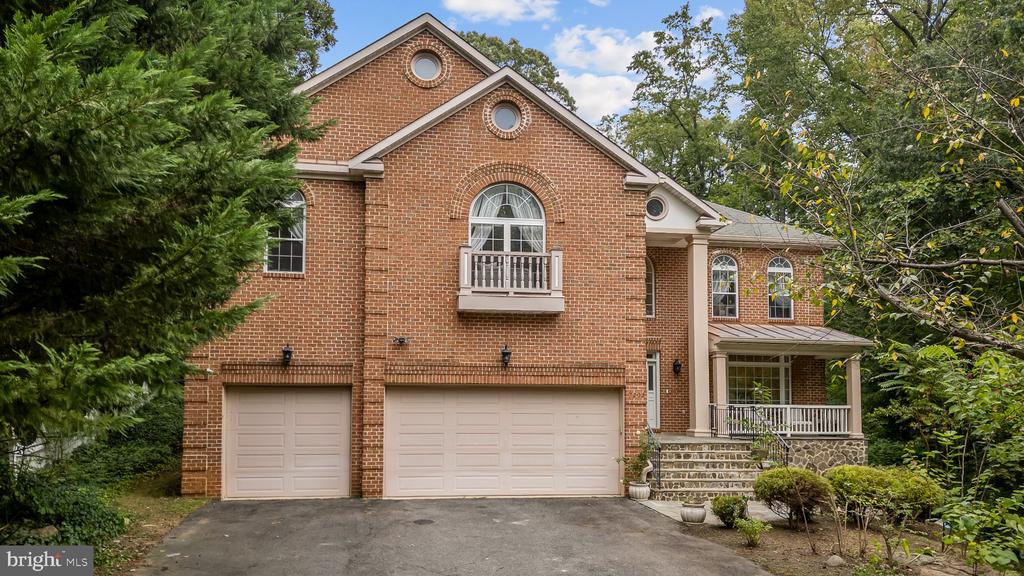 Red-brick house with a two-car garage, small balcony, and covered front porch.