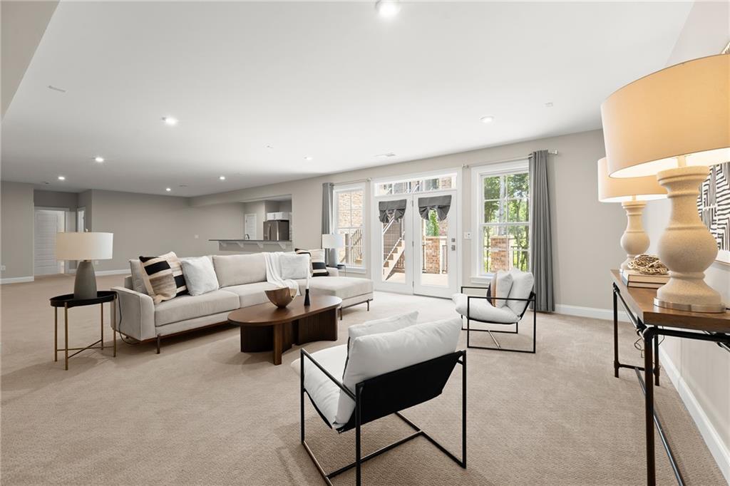 Staged living room with a light sectional, black-framed chairs, and French doors to a deck.