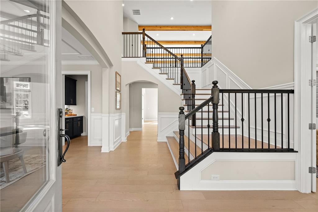 Two-story foyer with a sweeping staircase, dark balusters, and light wood floors.