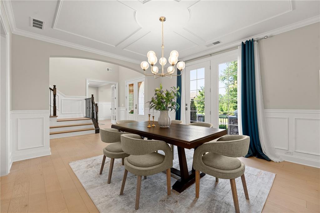 Dining room with a dark wood table, chandelier, and tall windows framed by blue curtains.