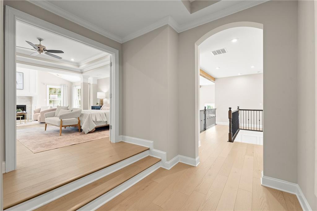 Foyer with light hardwood floors, a step-up living room, and an arched opening to an upstairs landing.