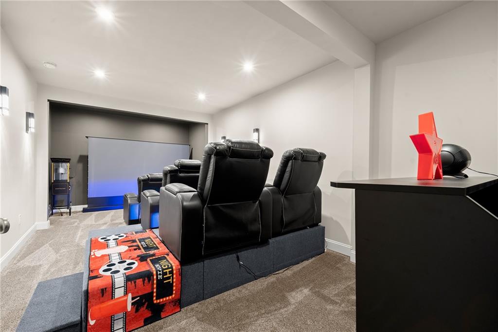 Home theater with black leather recliners facing a large projection screen and a colorful movie-night rug.