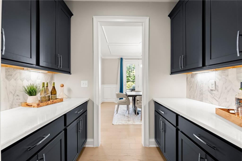 Kitchen pantry with navy cabinets and white counters, looking through to a dining area.
