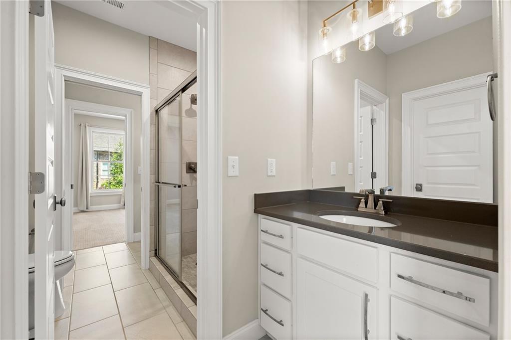 Bathroom with a white vanity, dark countertop, and glass-enclosed shower.