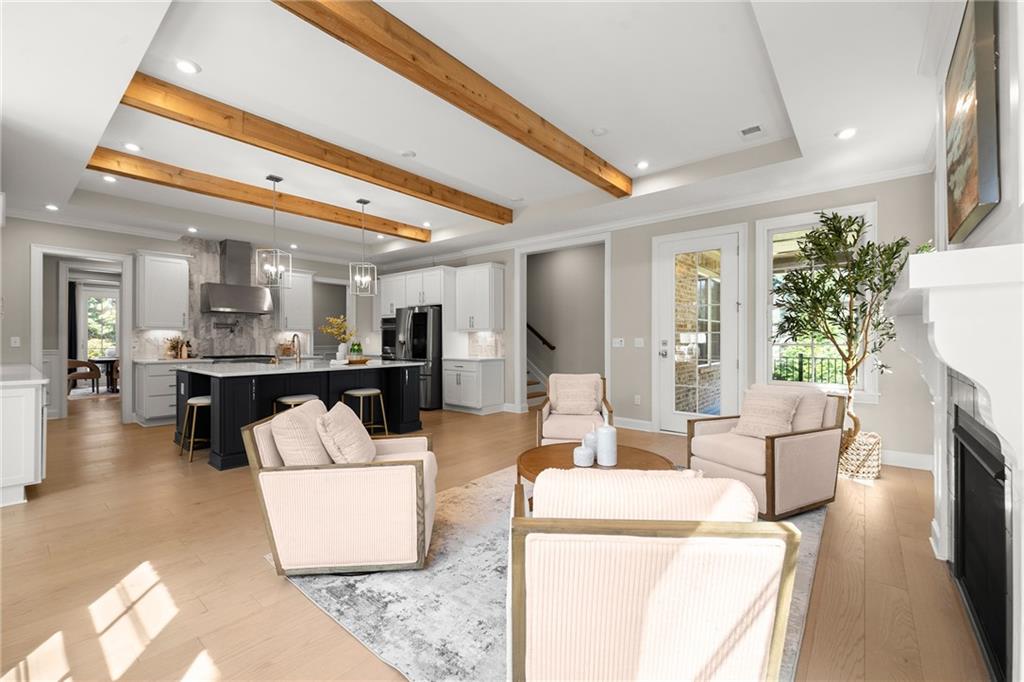 Open-plan living room and kitchen with exposed wood ceiling beams, a black island, and a fireplace.