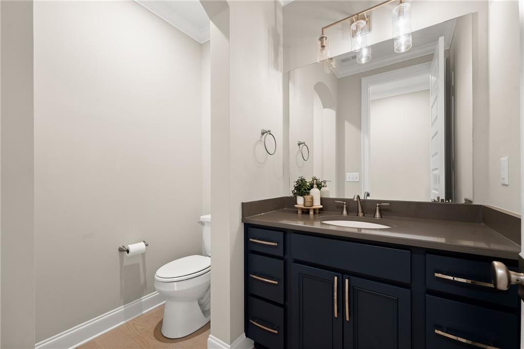 Bathroom with a navy vanity, large mirror, glass pendant lights, and a toilet alcove.