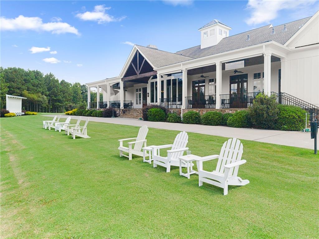 White clubhouse with a covered porch and Adirondack chairs arranged on the lawn.