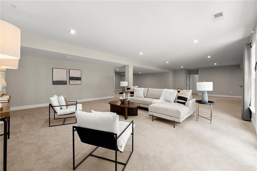 Spacious living room with a white sectional, black-framed chairs, and beige carpeting.