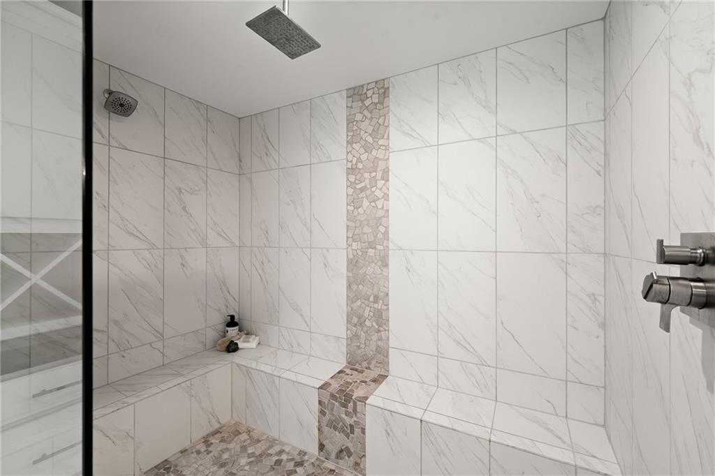 Marble-look tiled shower with a built-in bench and mosaic accent strip.