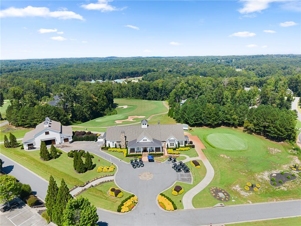 Golf course clubhouse surrounded by green fairways, sand bunkers, and wooded hills.