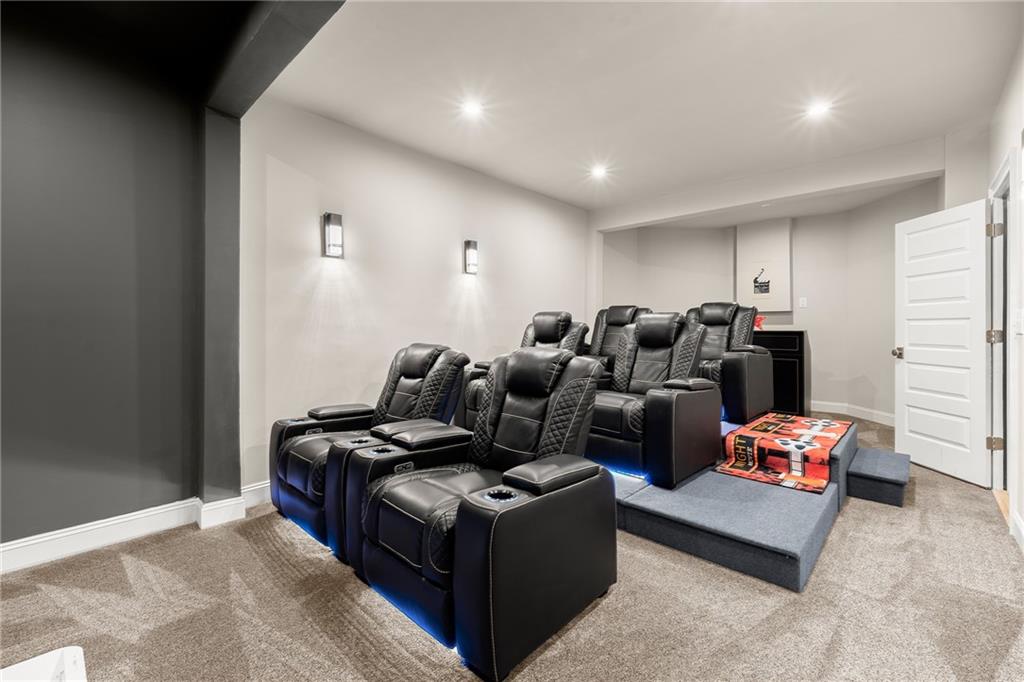 Home theater with rows of black leather recliners on a raised platform and blue accent lighting.