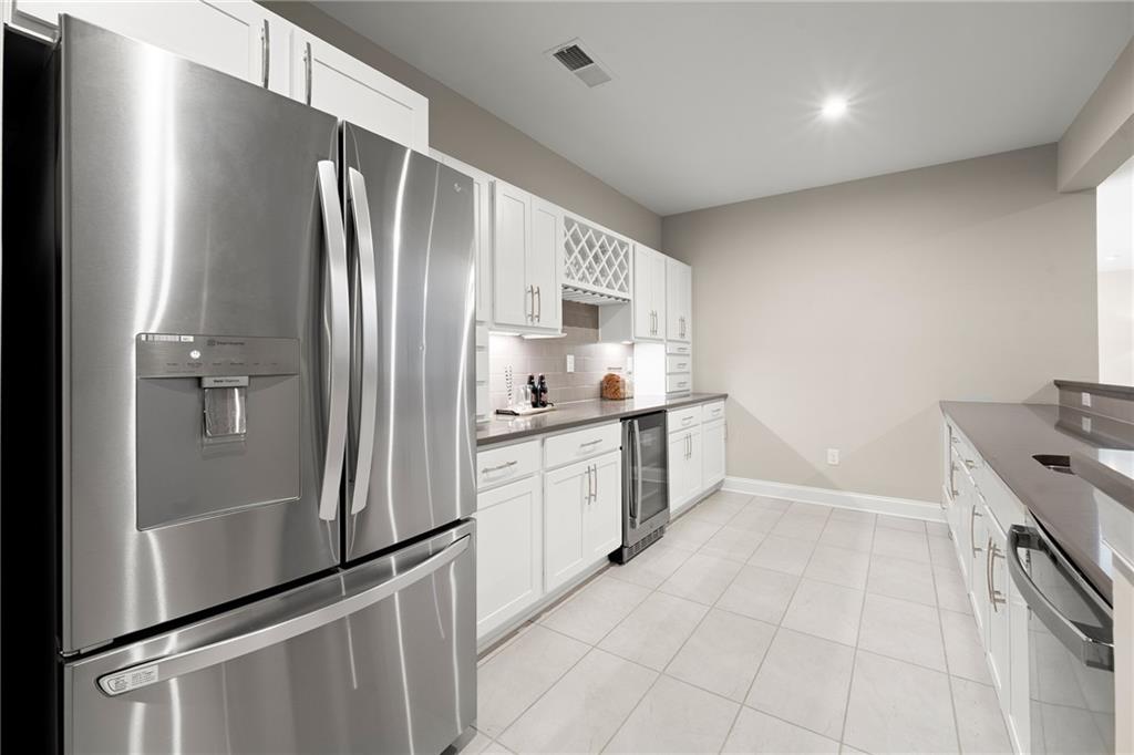 Galley kitchen with white cabinets, stainless steel appliances, and a built-in wine refrigerator.