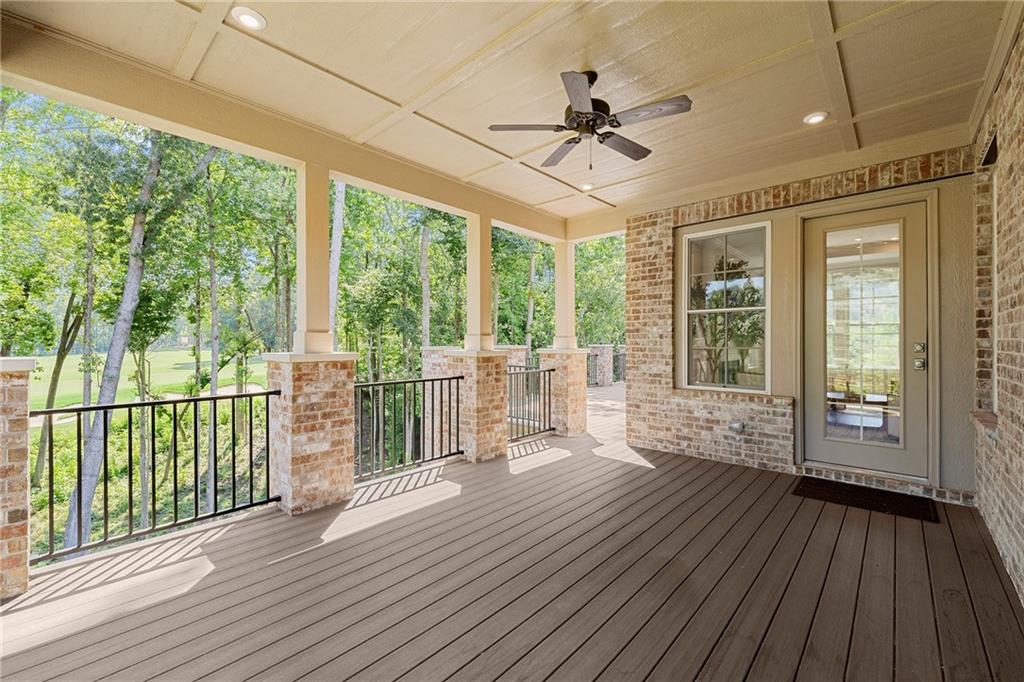 Covered porch with a wide plank deck, brick columns, and views of mature trees and lawn.
