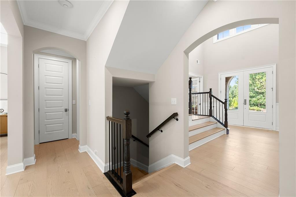 Entry hall with pale wood floors, a central staircase, and glass-paneled double doors.