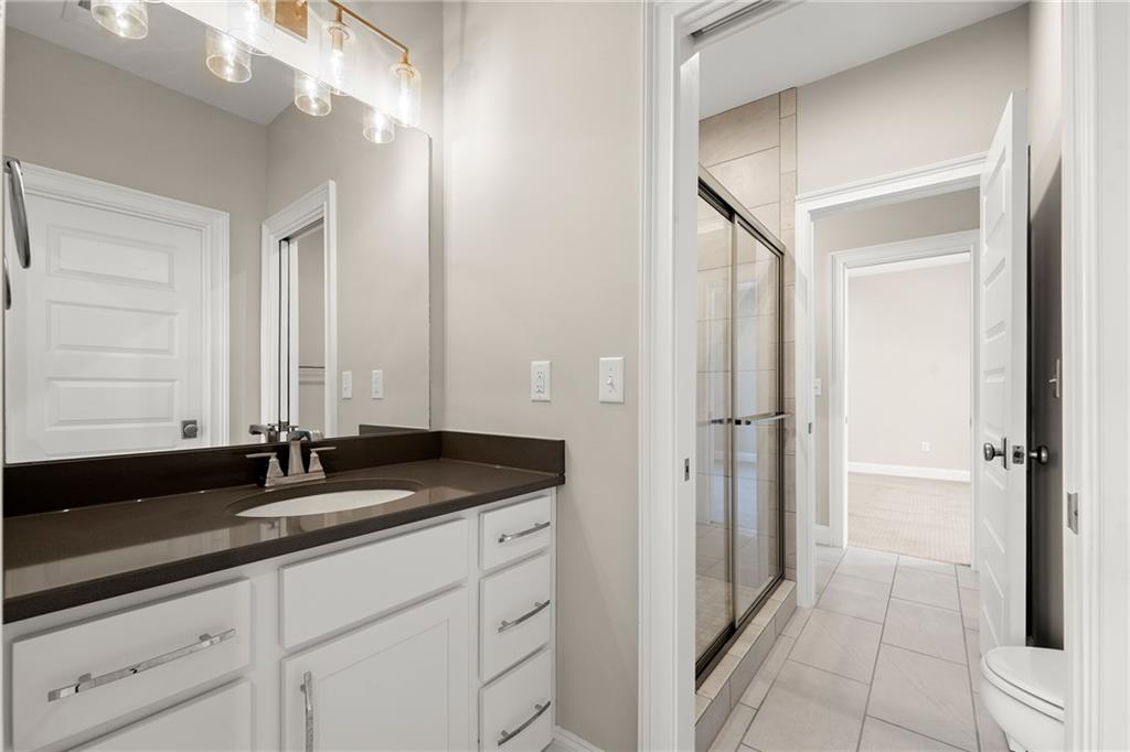 Bathroom with a white vanity and dark countertop beside a glass-enclosed tiled shower.