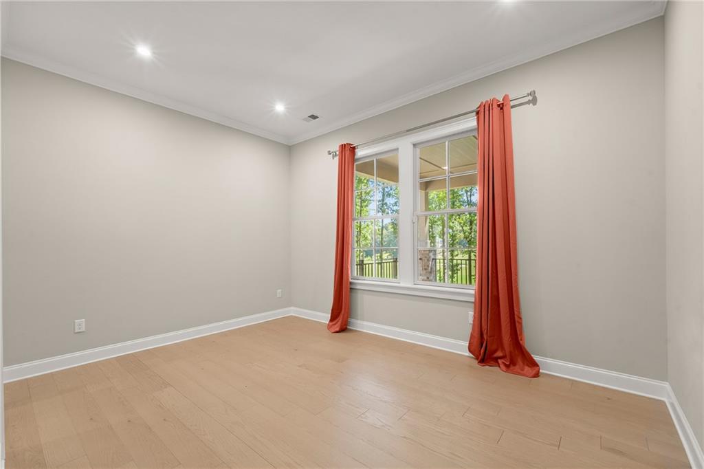 Empty room with pale wood floors and a large window framed by coral-red curtains.