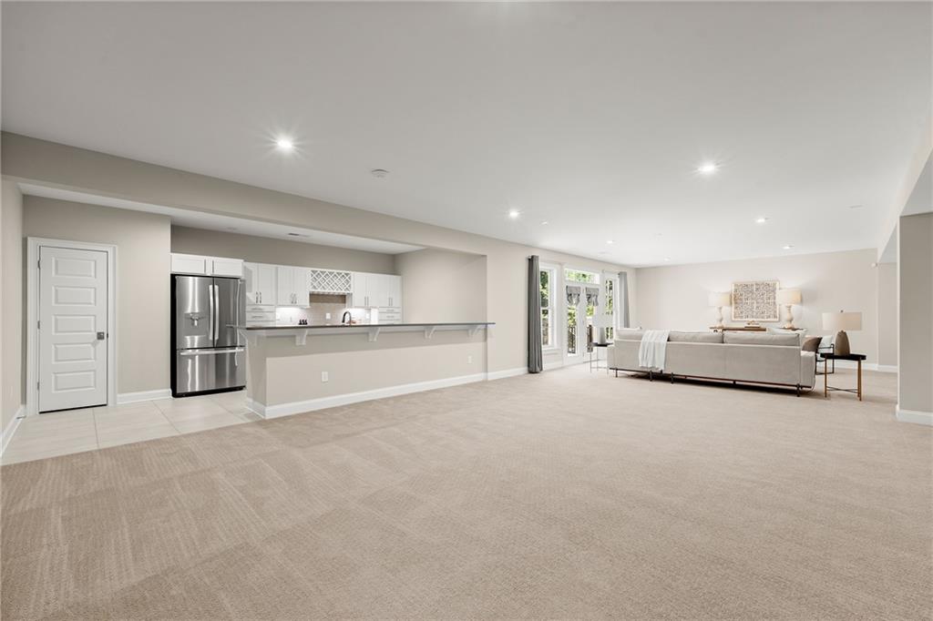 Open living area with a white kitchen, stainless refrigerator, and sofa seating area.