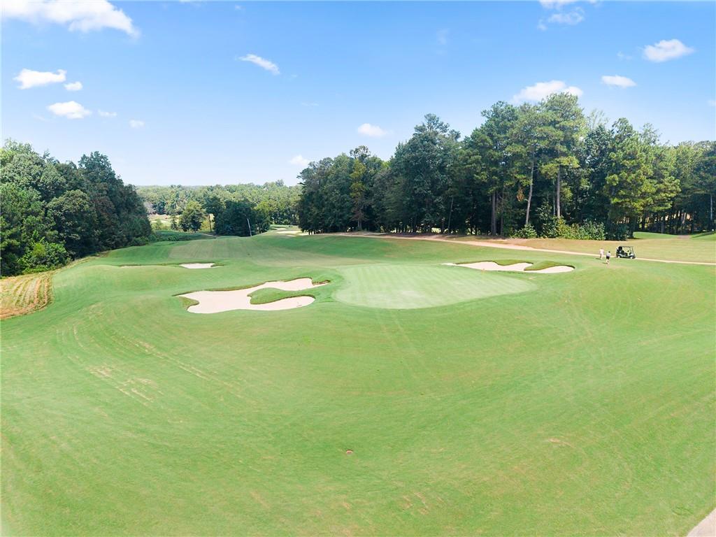 Golf course fairway with sculpted sand bunkers and a tree-lined edge.