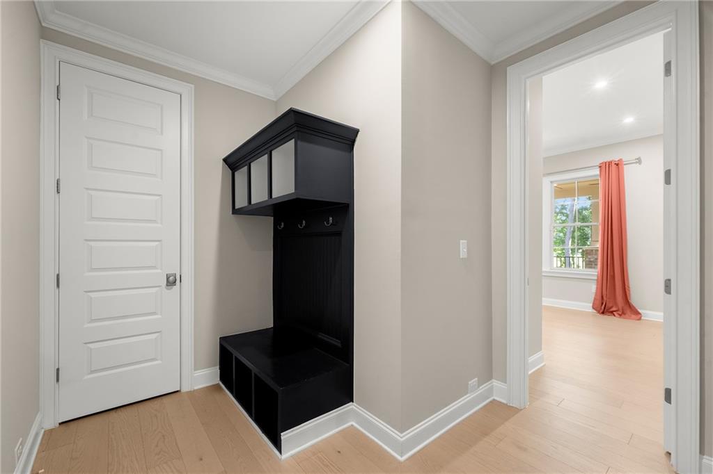 Entryway with a black built-in coat bench and an adjoining room with coral curtains.