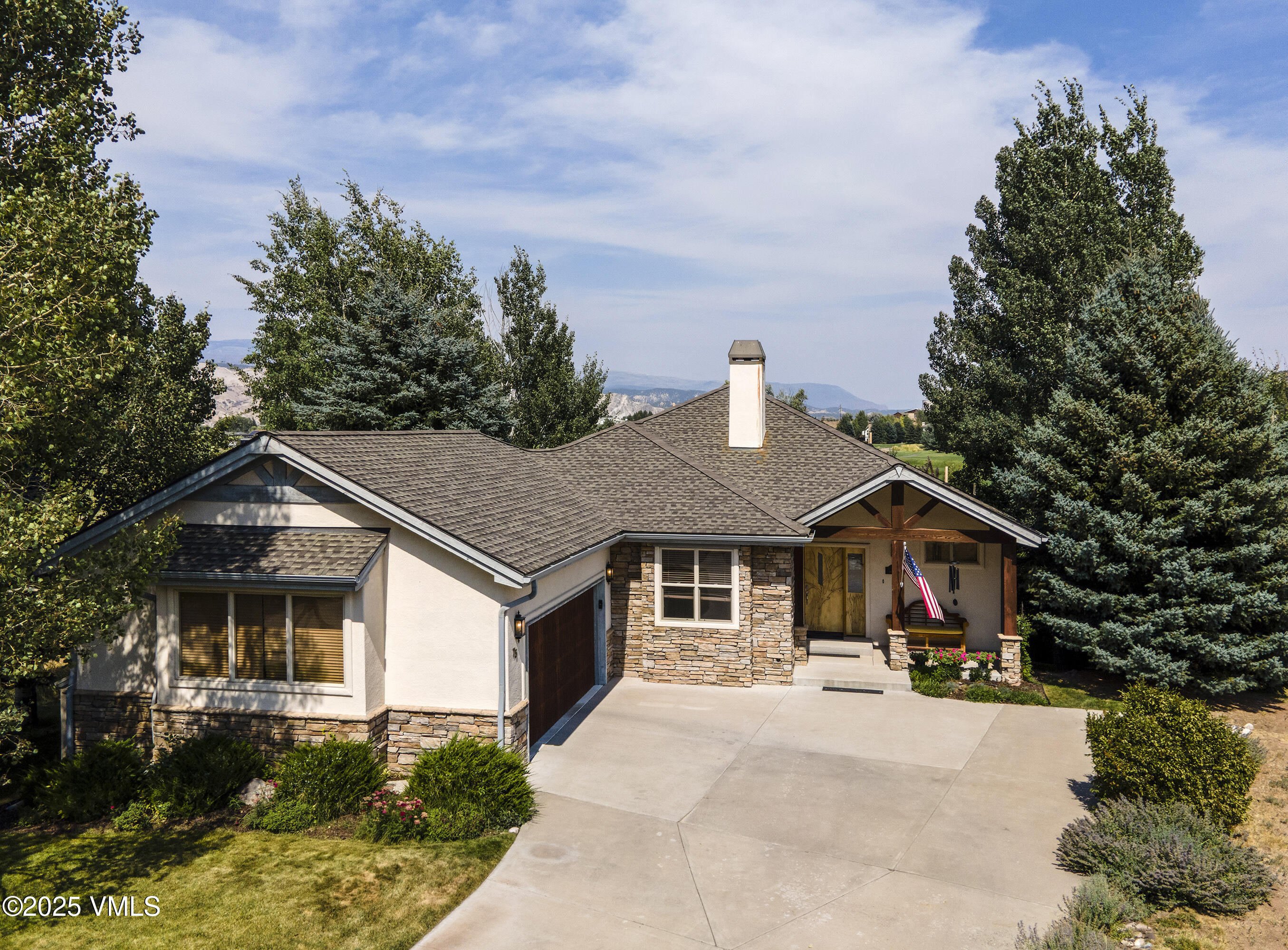 Stone-and-stucco home with a broad driveway, covered porch, and mountain views.