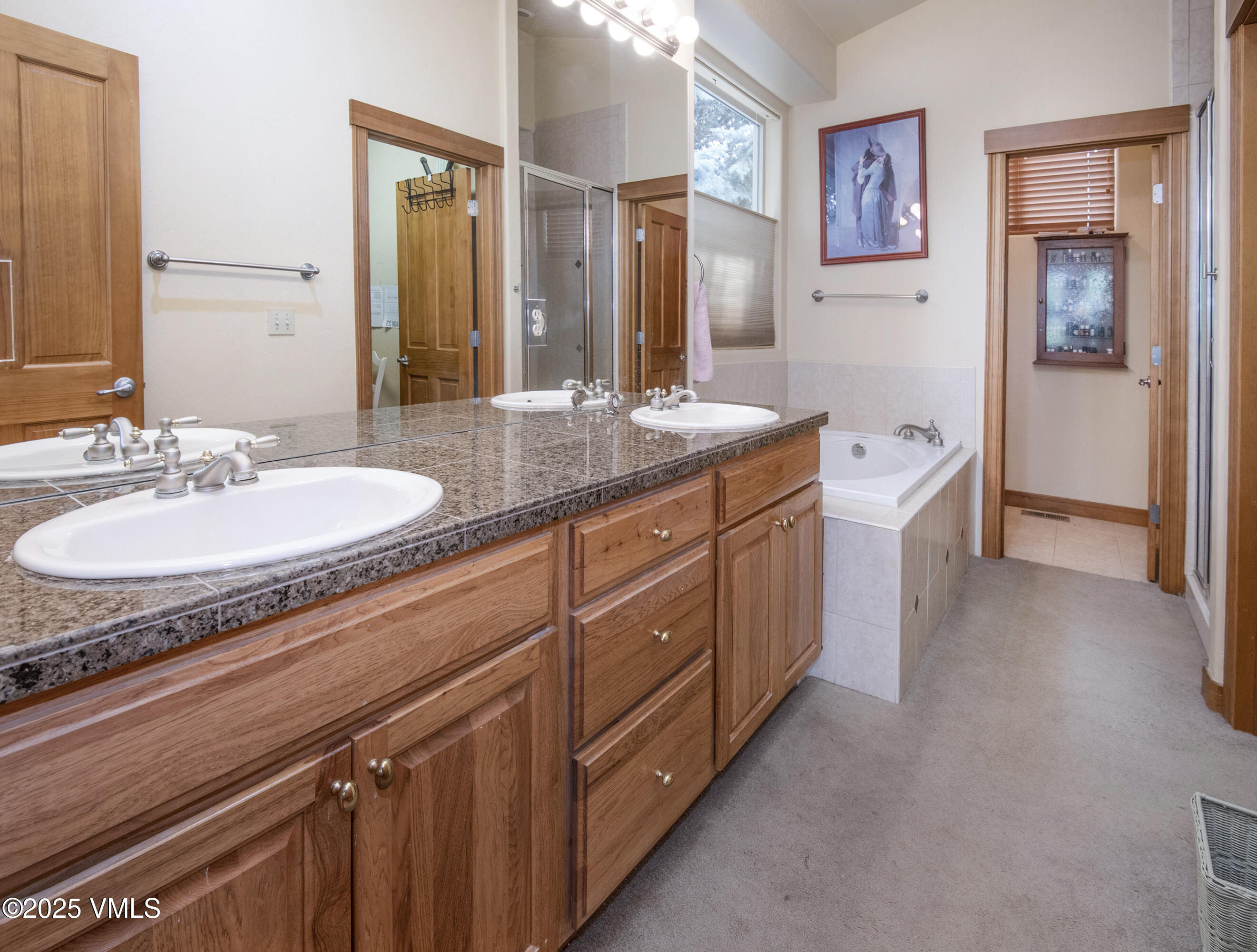 Bathroom with a long granite double-sink vanity and built-in soaking tub.