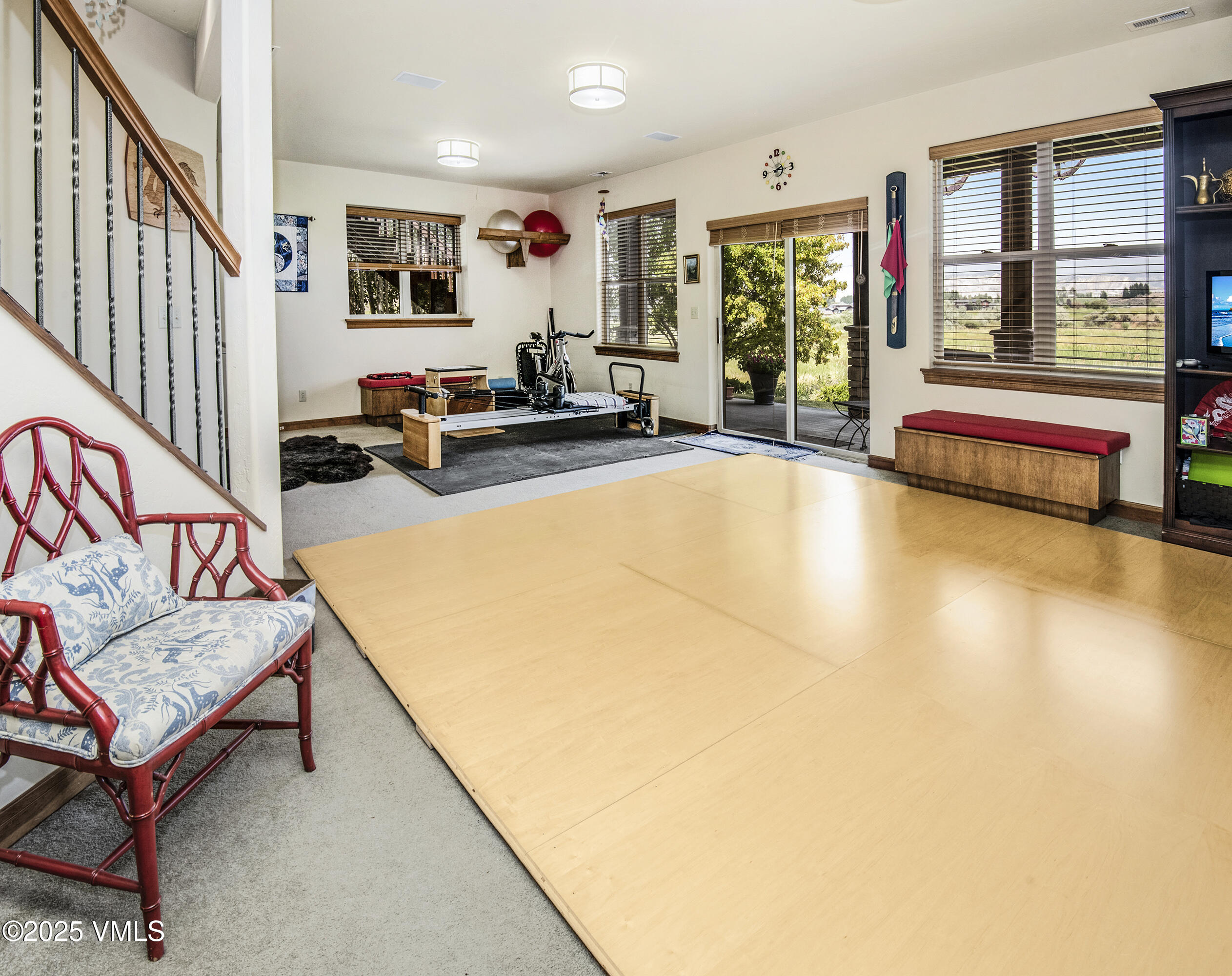 Recreation room with a large wood dance floor, Pilates reformer, and glass doors to the garden.
