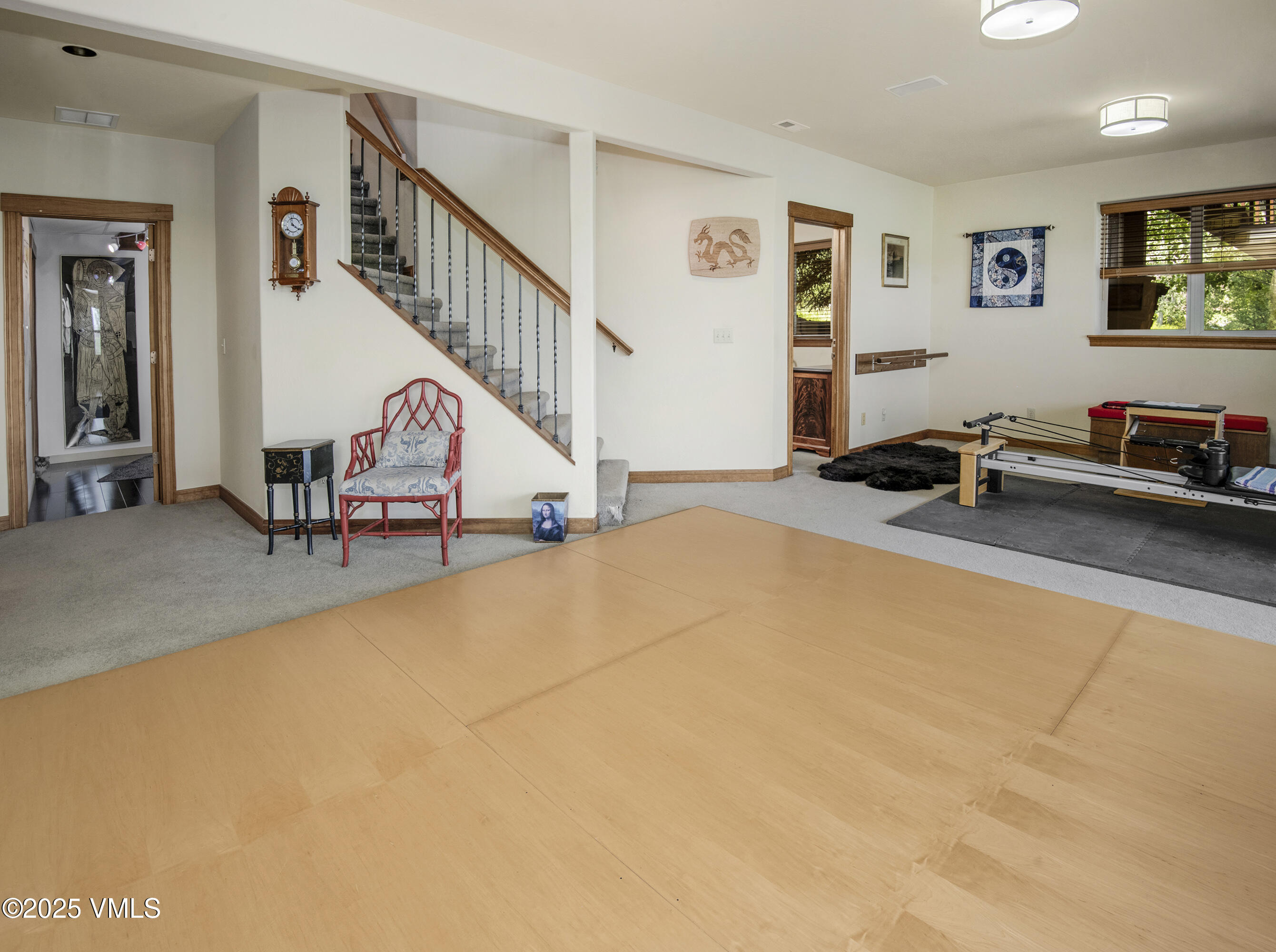 Exercise room with a large wood floor, Pilates reformer, and staircase with wood railing.
