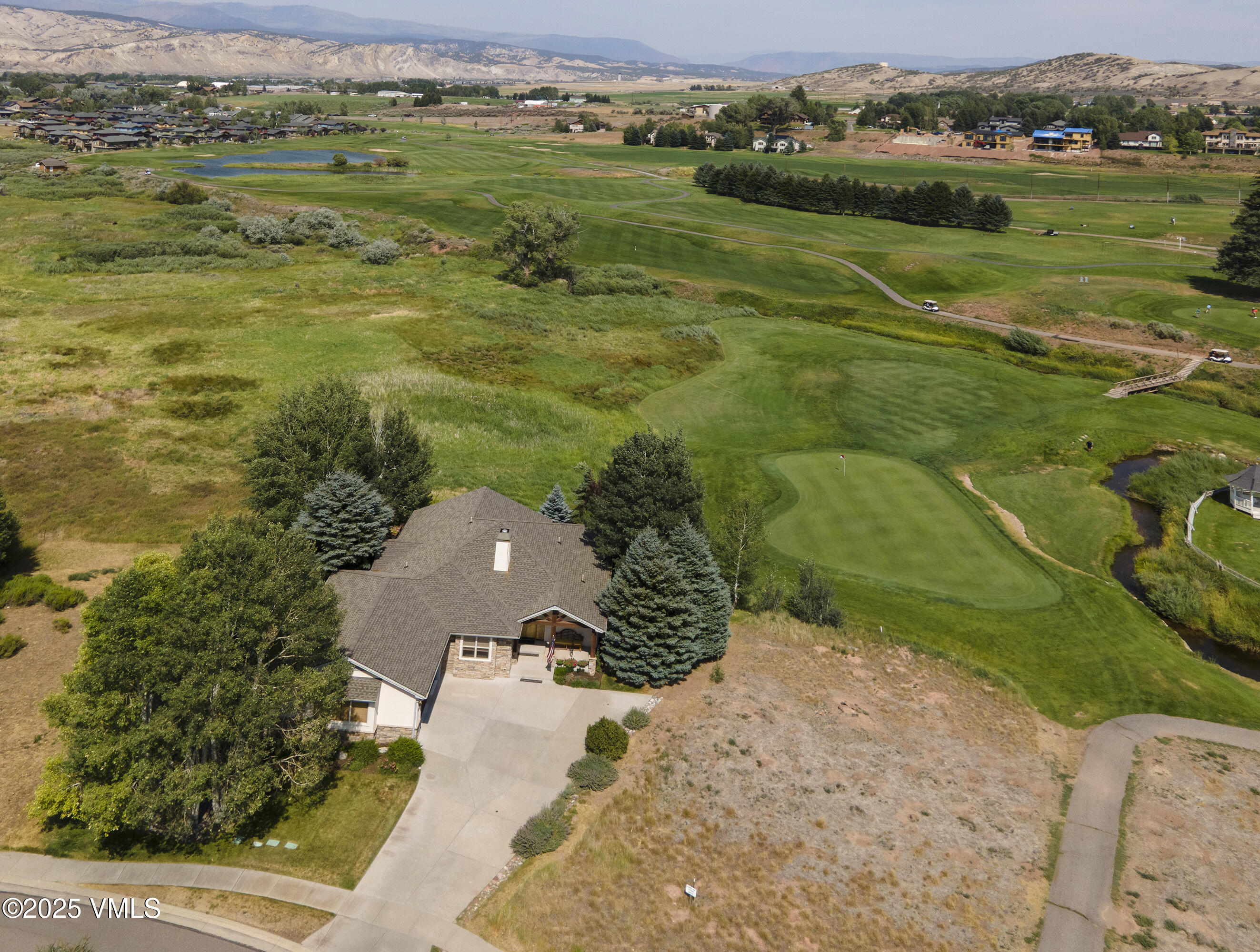 Home beside a golf course, with a winding cart path and foothills beyond.