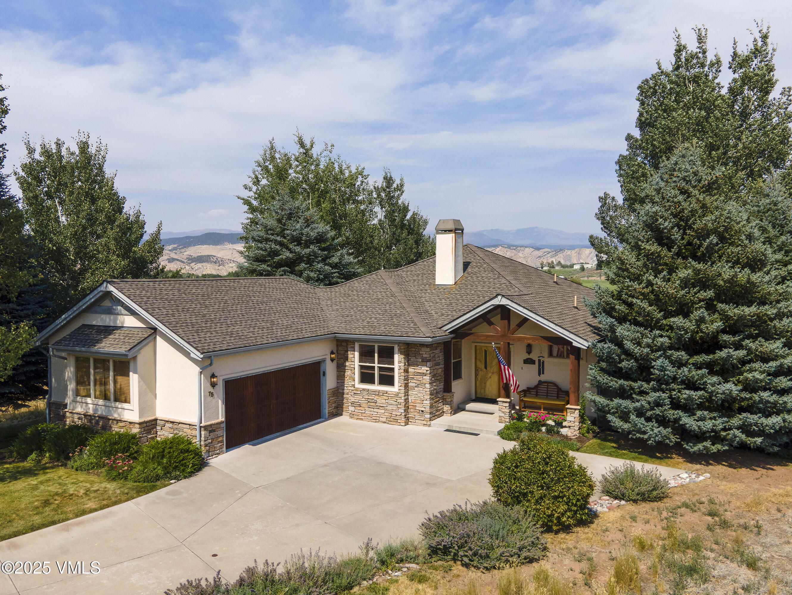Single-story stucco home with stone accents, attached garage, covered entry, and distant mountain views.