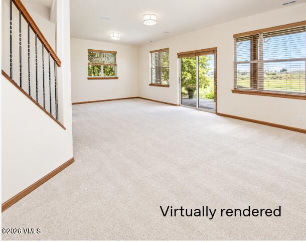 Empty living room with light carpet, wood trim, and windows beside a sliding glass door.