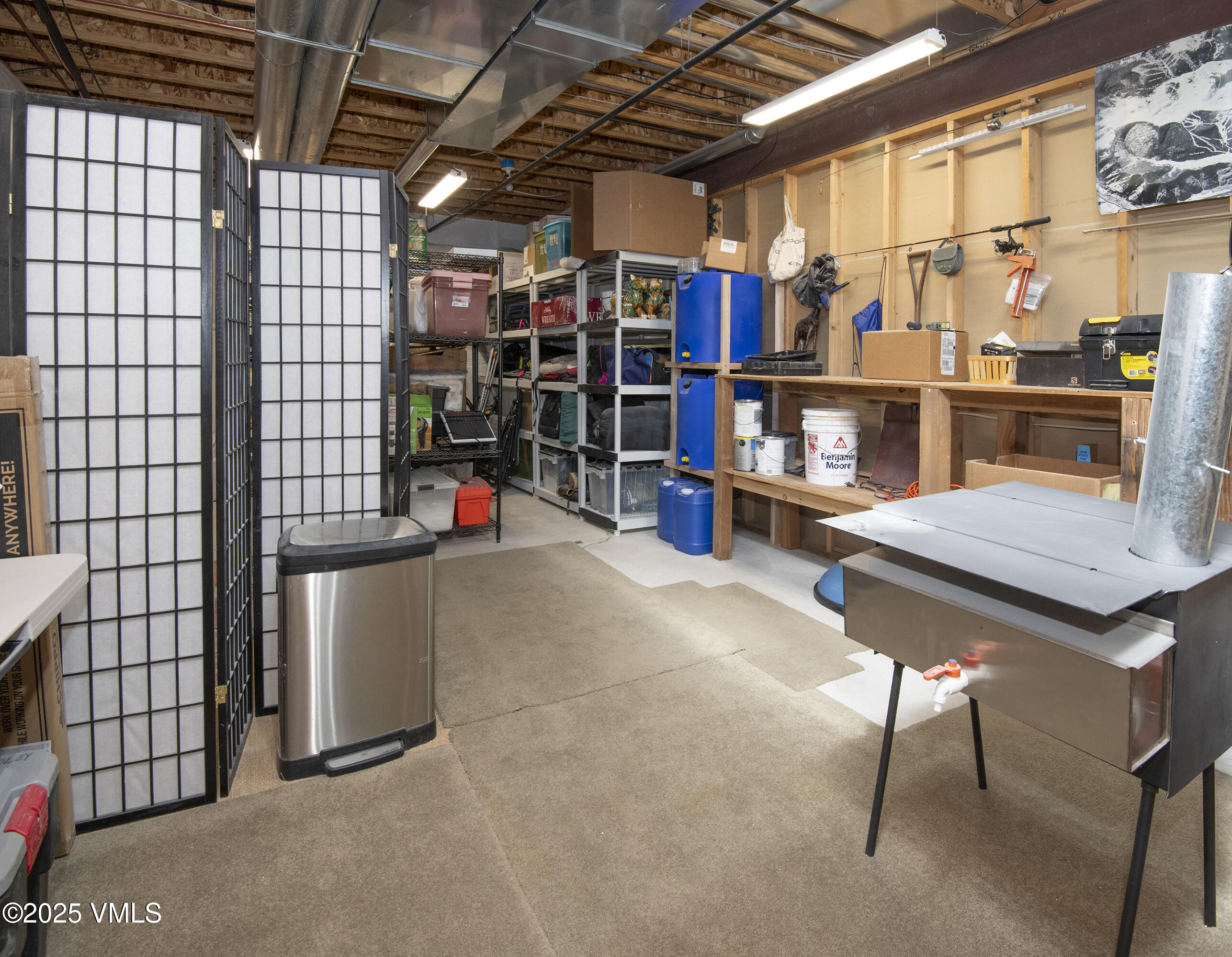 Utility room with extensive shelving, a wooden workbench, and a freestanding stainless-steel sink.