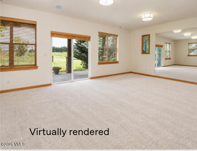 Empty carpeted living room with wood-trimmed windows, a patio slider, and an adjoining room.