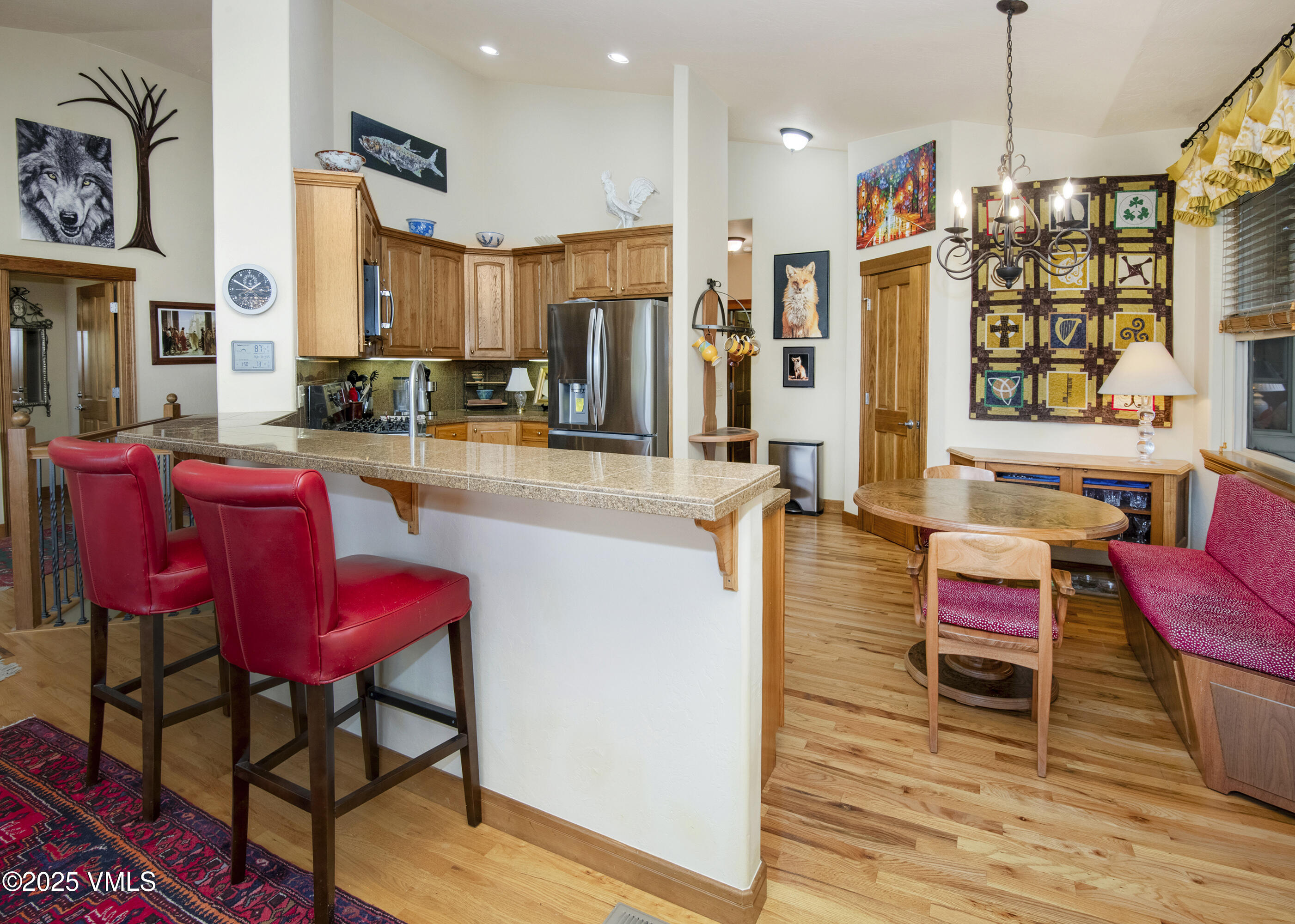 Open kitchen and dining area with a granite breakfast bar, red stools, and a cozy sitting nook.
