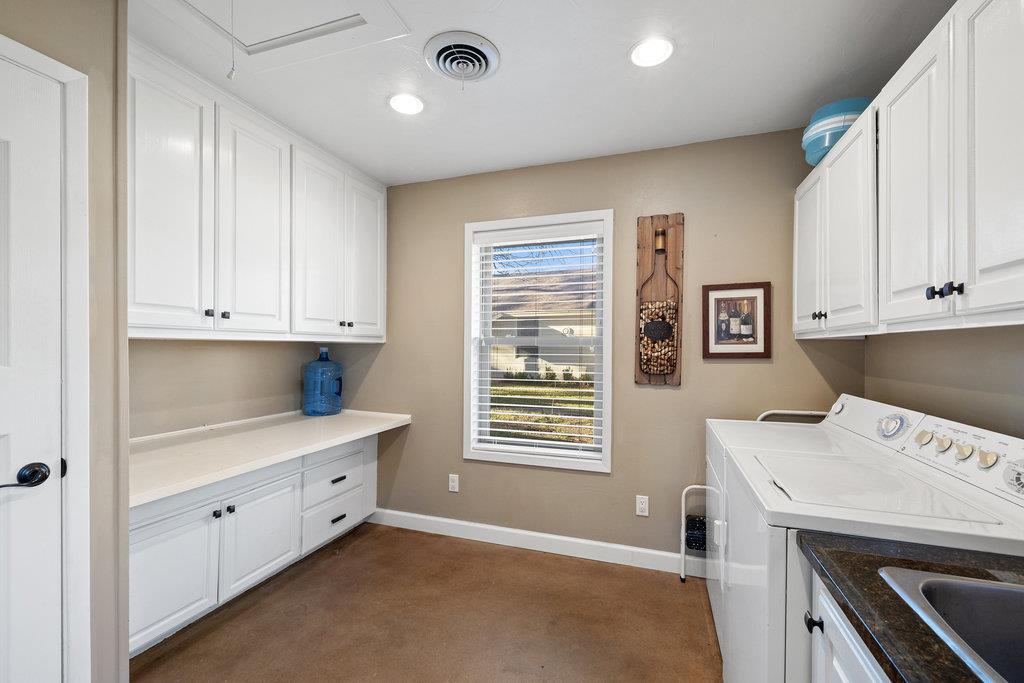 Laundry room with white cabinets, a window, and washer and dryer.