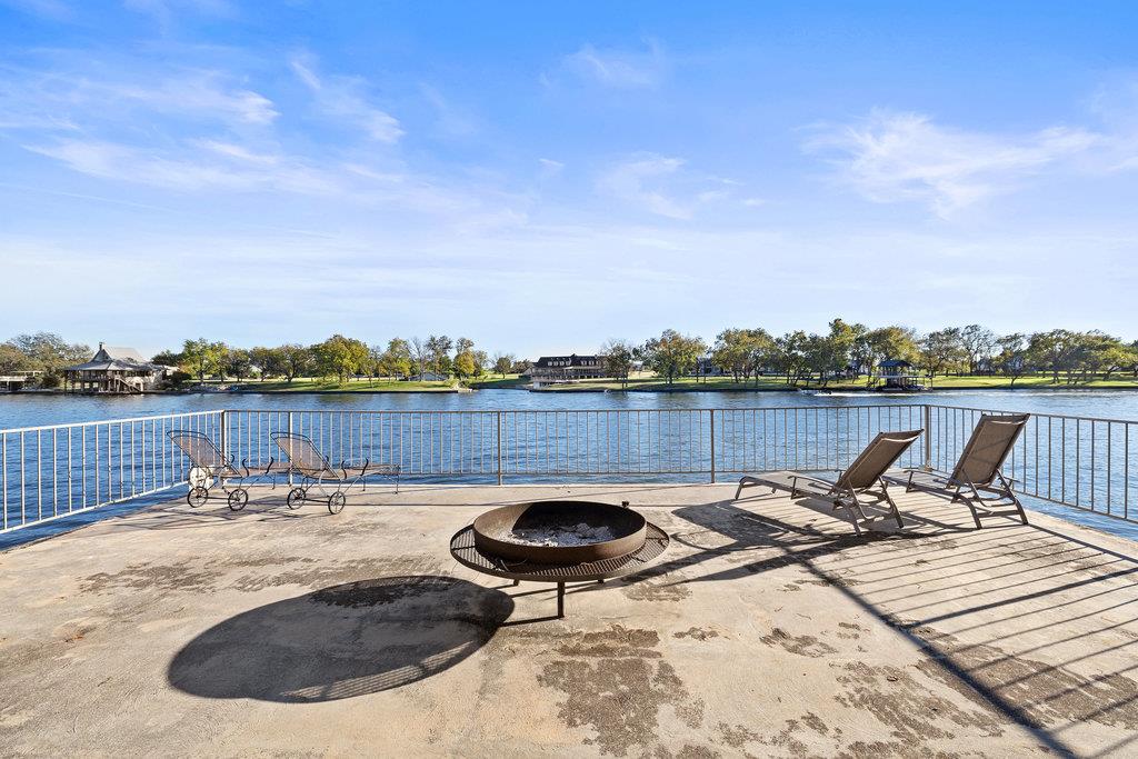 Waterfront patio with a circular fire pit, lounge chairs, and lake views.