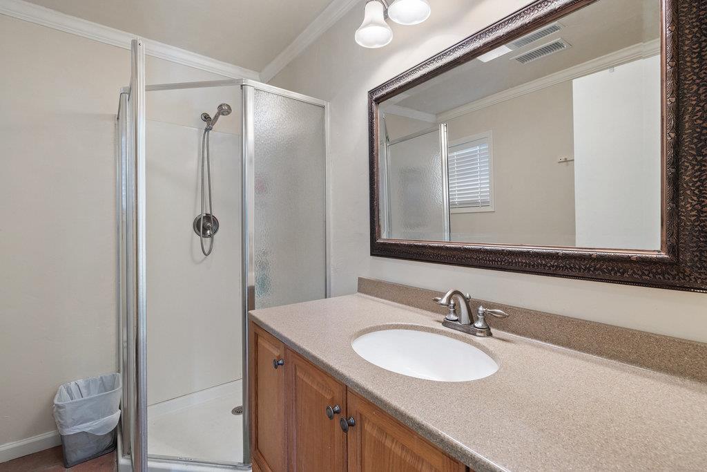 Bathroom with a glass shower, wood vanity, and large framed mirror.