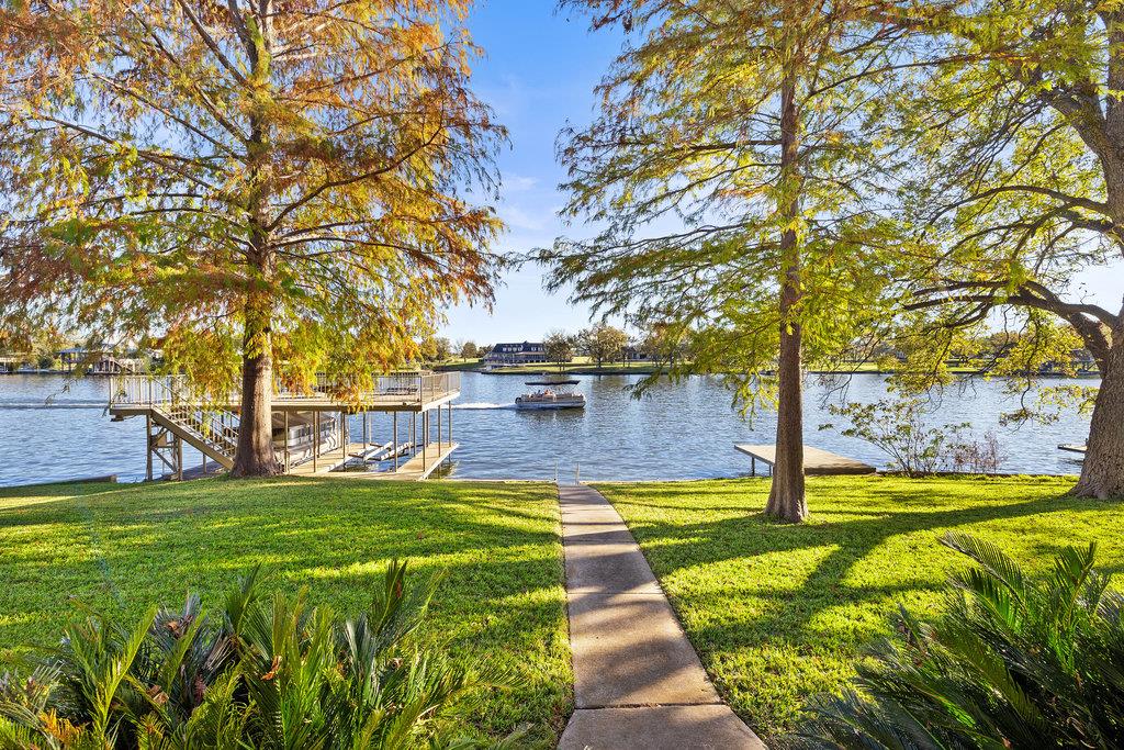 Waterfront yard with a path leading to a covered dock and boat on the lake.