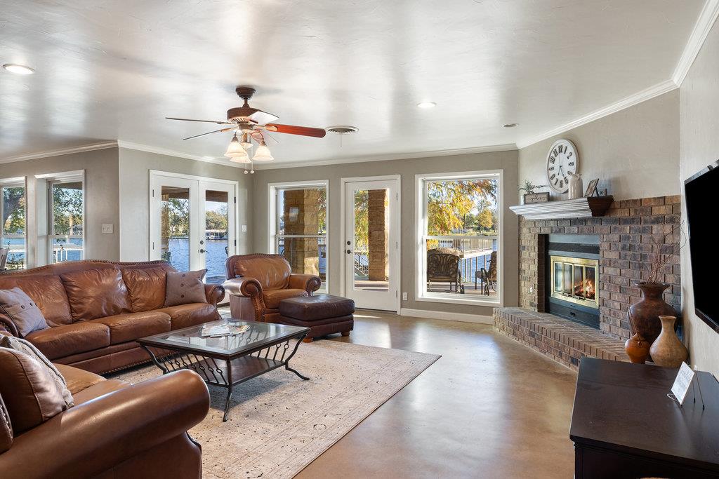 Living room with leather seating, a brick fireplace, and large windows overlooking the lake.