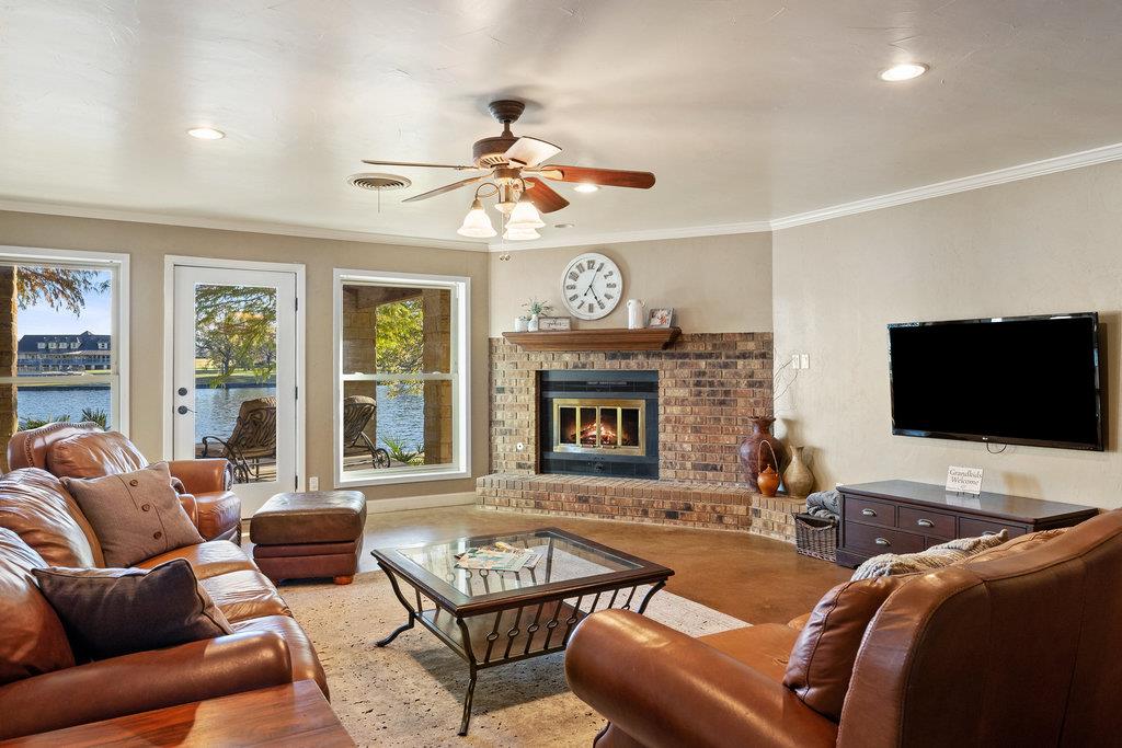 Living room with leather seating and brick fireplace overlooking the water through large windows.