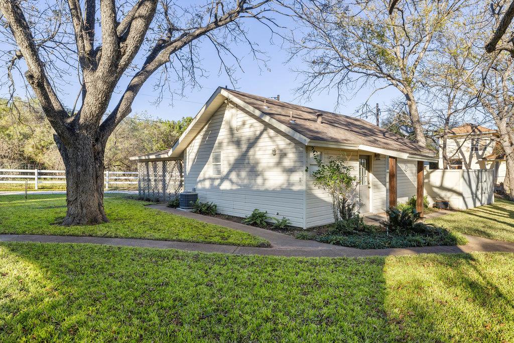 Single-story house with a covered entry and a large shade tree in the grassy yard.