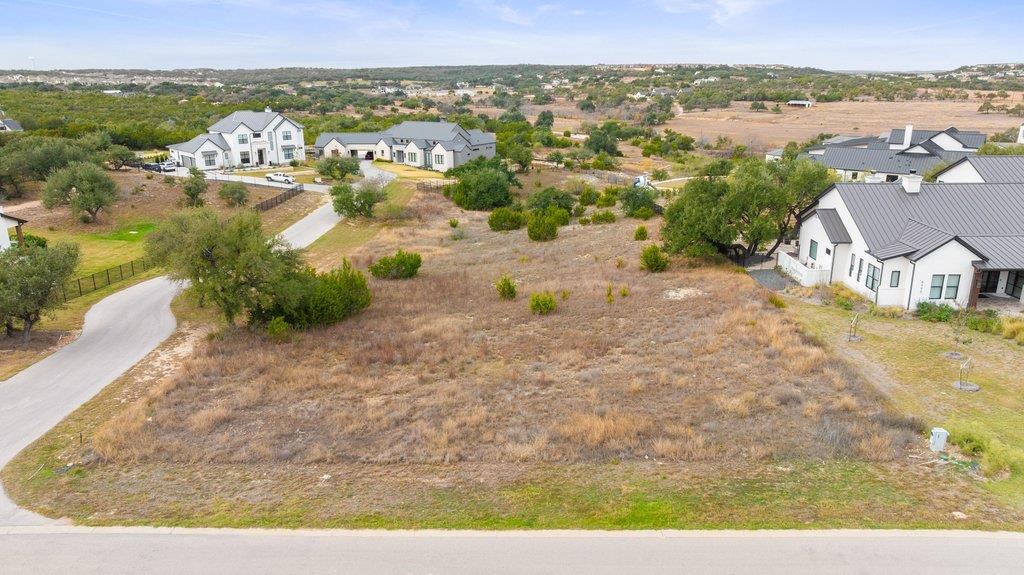 Aerial view of a vacant lot beside a road, with white houses nearby.