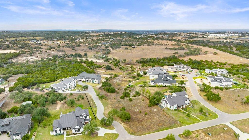 Aerial view of homes and curving streets amid open fields and wooded areas.