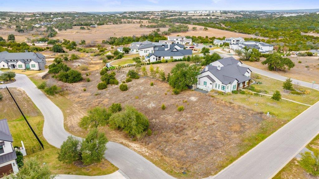 Aerial view of a vacant lot among homes and paved roads in a dry neighborhood.