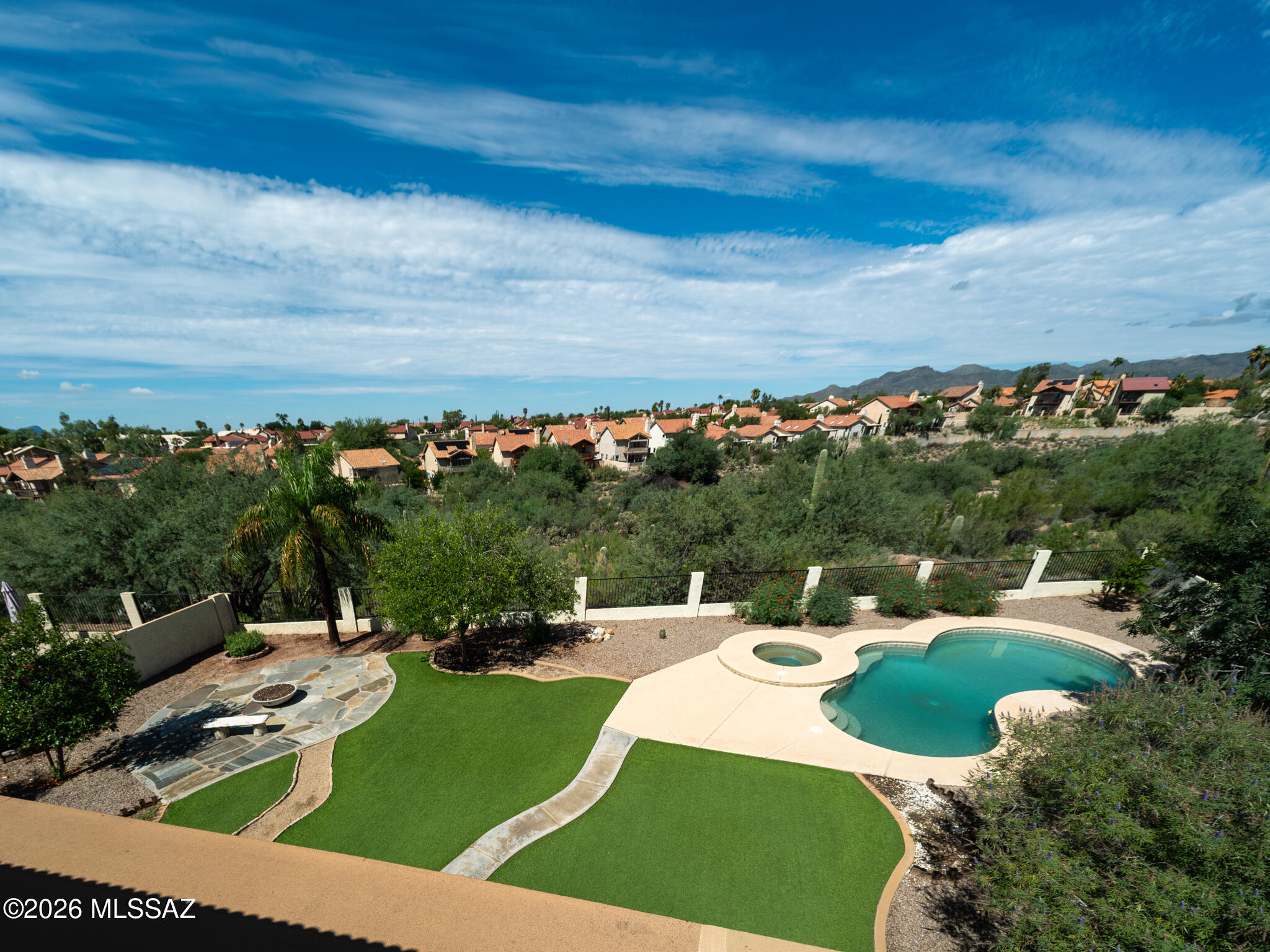 Backyard pool and spa with artificial turf, a stone fire-pit patio, and mountain views.
