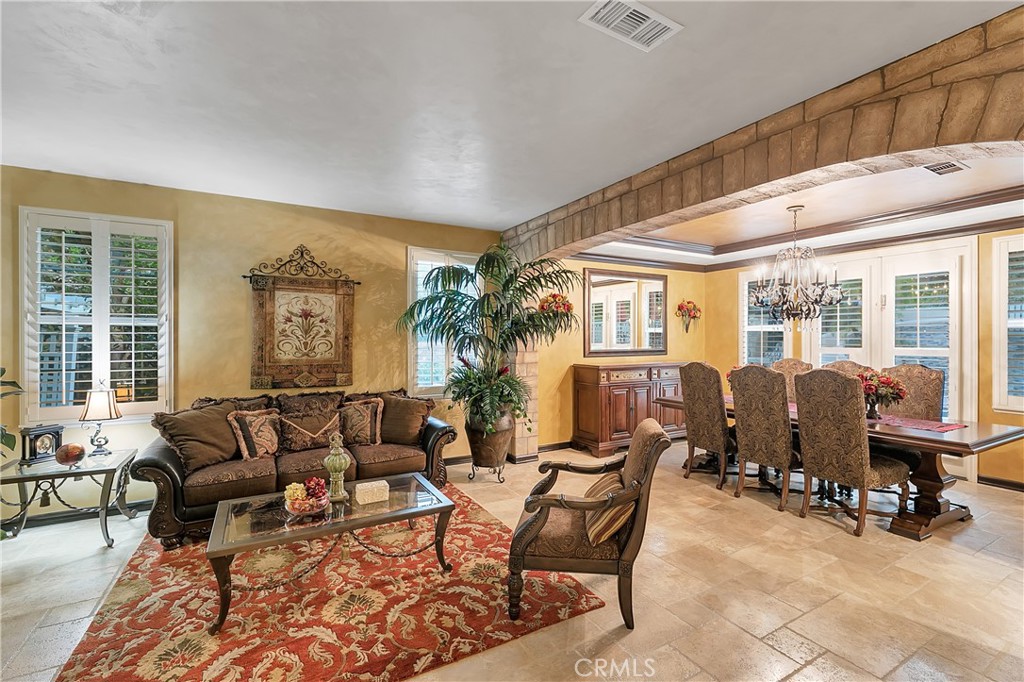 Furnished living and dining room with a brown sofa, red patterned rug, and long wooden dining table.