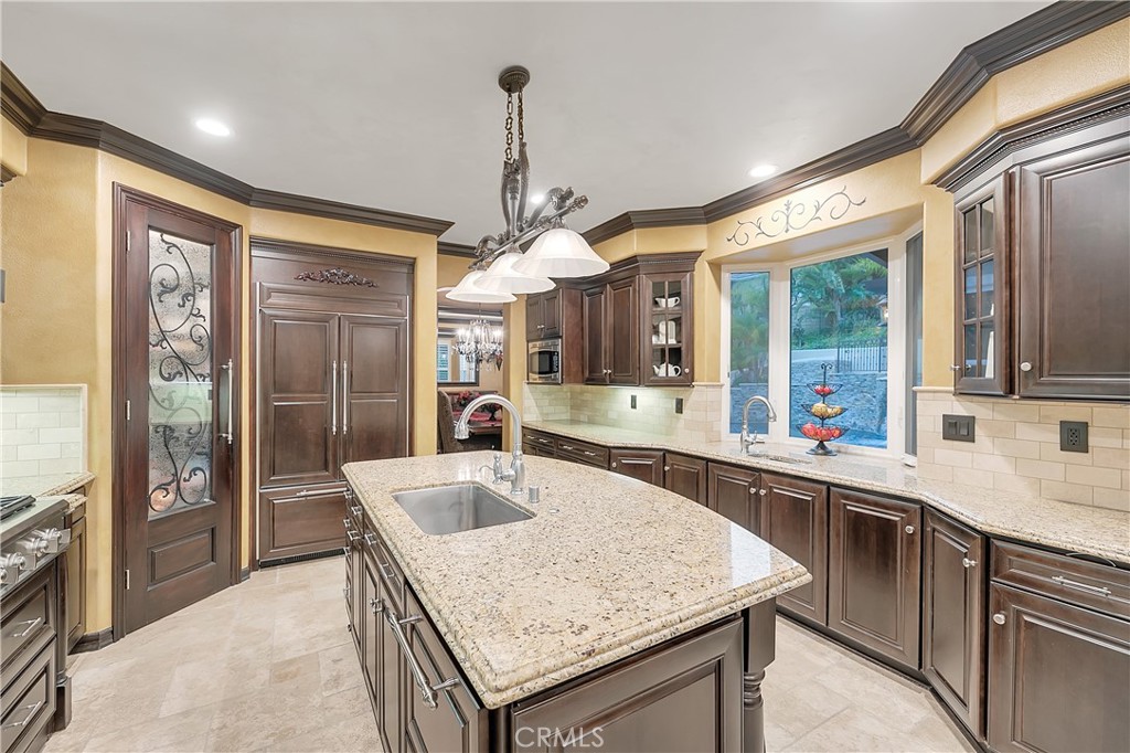 Kitchen with a granite island, dark wood cabinetry, and a window overlooking greenery.