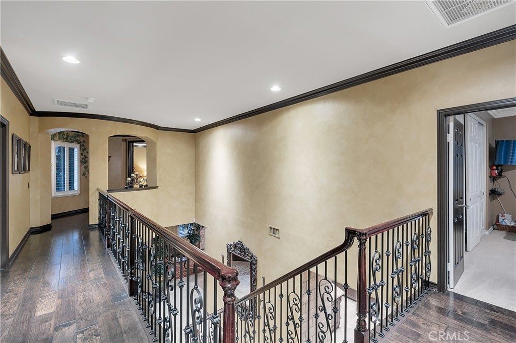 Upstairs hallway overlooking a staircase with ornate black metal balusters and dark wood handrails.