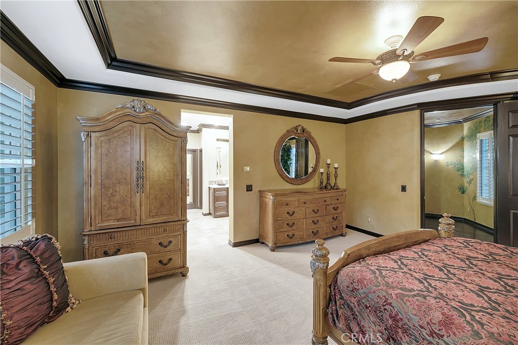 Bedroom with carved wooden furniture, a patterned bedspread, and an ornate tray ceiling.